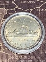 Obverse side of 1935 Canadian silver dollar coin showing the two men in a canoe with the year 1935 below, 'CANADA' at the top and 'DOLLAR' at the bottom.