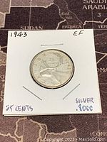 Front view of the 1943 Canadian 25 cents silver coin showing the caribou and denomination with year.