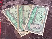 Three 1954 Canadian one dollar banknotes viewed from front showing text and Queen Elizabeth II portrait
