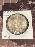 Front side of the 1959 Netherlands 2 1/2 Gulden coin showing the crowned lion and denomination.