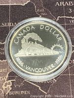 Obverse of the coin showing a steam locomotive train with 'CANADA DOLLAR 1886 VANCOUVER 1986' inscription
