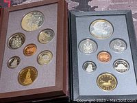 Two Canadian proof coin sets displayed in open protective cases showing multiple coins including silver dollars with detailed engravings.