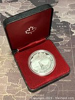 Silver 1 Dollar coin with case open showing red velvet interior and coin in clear protective capsule.