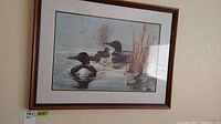 Framed art print showing three common loons and chicks in water with reeds.