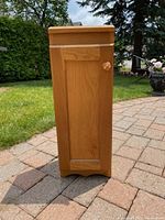 Front profile of wood media storage cabinet showing paneled door with knob.