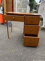 Side view of wood desk showing open drawers and metal knobs
