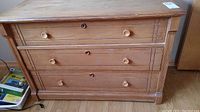 Front view of vintage wooden dresser with 3 drawers and wooden knobs, showing drawer details and wear.