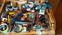 Mixed hand tools, sockets, brushes, screws, and strapping piled on a table