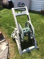 Overall view of Ames Reel Easy hose reel with hose on grass outdoors.
