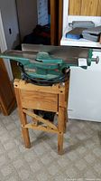 Full view of the green vintage planer on wooden stand, showing overall structure and size.