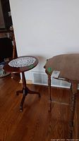 Round pedestal table with a lace doily on top and part of the half moon table visible nearby.
