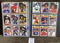 Two binder pages showing multiple 1985-86 O.P.C. hockey cards including Wayne Gretzky, Pelle Lindbergh, Steve Yzerman and others arranged in plastic sleeves.