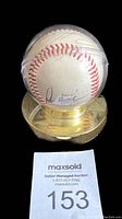 Baseball in plastic case on gold-colored display stand showing Pedro Martinez signature prominently.