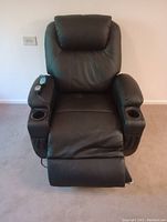 Front view of the black electric massage recliner chair with footrest extended, showing remote control on left armrest and cup holders on both armrests.