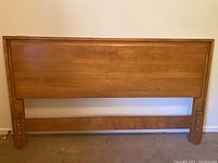 Front view of Mid Century Modern full size wooden headboard showing smooth panel design and metal mounting hardware on sides.