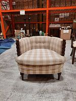 Front view of upholstered armchair with plaid fabric and wood frame showing overall design.