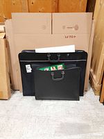 Large and smaller black art portfolios side by side. Smaller portfolio holds sticker sheets visible inside.