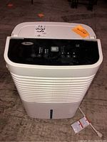 Front view of white Whirlpool Gold dehumidifier with black control panel on top and power cord visible above floor.