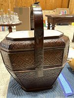 Front view of the woven wicker hamper with stone tile top and integrated wooden handle