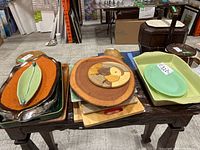 Overview photo showing multiple serving platters, wooden cutting boards, and ceramic dishes arranged on a wooden table