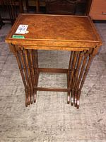 Front view of all four nested tables showing veneered top and spindle legs.