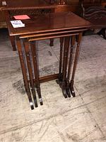 Set of three wooden nesting tables stacked together showing the shape and finish.