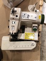 Top view of Reliable 174 serger showing model number and scale on arm with safety labels.