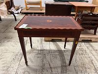 Front view of the veneered wood side table showing the pie crust edge detail and tapered legs