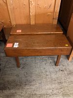 Two vintage wooden benches side by side on a concrete floor, showing the top surfaces, legs, and wood grain with wear and scratches.