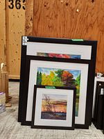 Three framed watercolour paintings stacked leaning against a wall showing size difference.