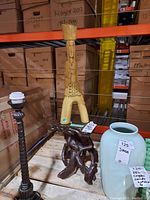 Wood painted stand and sculpture displayed on a pallet with visible warehouse background