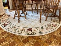 Full view of the round carpet under kitchen table and chairs showing the floral border and diamond patterned center.