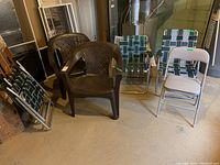 Photo showing two brown plastic lawn chairs, one white folding metal and vinyl chair, and four green and white plastic mesh foldable lawn chairs.