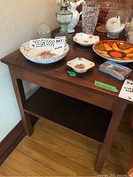 Wood side table with lower shelf, showing the top surface, legs, lower shelf, and Honderich mark. No items on the lower shelf, some decorative objects on the table.