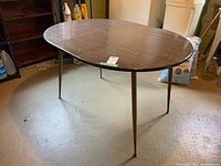 Full view of the oval kitchen table with laminate top and chrome legs showing the overall condition and the shape.