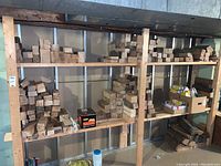 Wood pieces stacked on wooden shelves in basement, assorted sizes mostly smaller pieces like 2x4, 3x3, 3x4