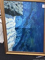 Front view of one oil painting showing blue and white canvas with gold embossed frame and some flaws