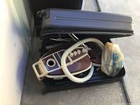 Packed vacuum cleaner in black suitcase