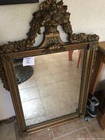 Front view of the rectangular mirror showing the detailed golden embossed frame with grape leaves and floral decorations on the top and sides.