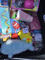 Overview of the lot showing plush whale, grow snake toy, popcorn containers, yellow chick toy, and other assorted toys