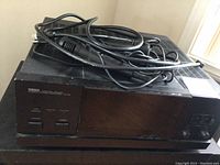 Black Yamaha M-60 power amplifier with cables on top, showing front panel and power button.