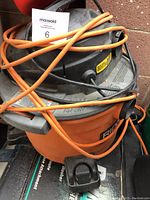 Photo of orange and black Rigid 4 gallon wet/dry shop vacuum with cords