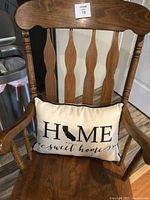 Front view of wooden rocking chair showing detailed carved back and pillow with 'HOME sweet home' text.