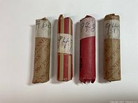 Photo showing four rolls of wheat pennies in paper wrappers with handwritten year and mint marks (1946S, 1947, 1948, 1949).