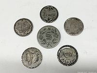 Top-down photo showing six silver hand engraved love tokens arranged in circle on white background