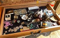 Wide shot of a tray with a variety of small items including jewelry, coins, pipes, and small memorabilia pieces spread out on a black cloth.