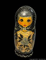 Hand painted female face on largest doll with black background and floral decoration