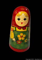 Close-up photo showing one of the dolls featuring a red headscarf and green floral apron, hand-painted detailing on surface.