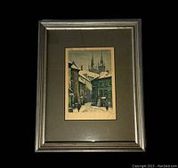 Framed pencil signed print showing a snowy cityscape with old buildings and church spires, against a black background.