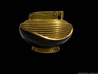 Side view of the vintage Ronson Lotus table lighter highlighting the curved ribbed brass top and black jet glass base with reflective surface.